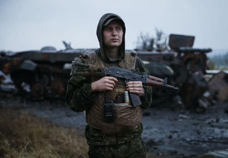 A Ukrainian soldier stands near a destroyed military vehicle of pro-Russian separatists just outside the eastern Ukrainian town of Slaviansk, July 7, 2014. REUTERS/Gleb Garanich