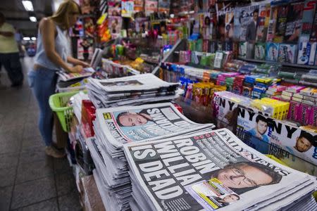 A woman looks at magazines just past newspapers announcing the death of comedian Robin Williams in New York August 12, 2014. REUTERS/Lucas Jackson