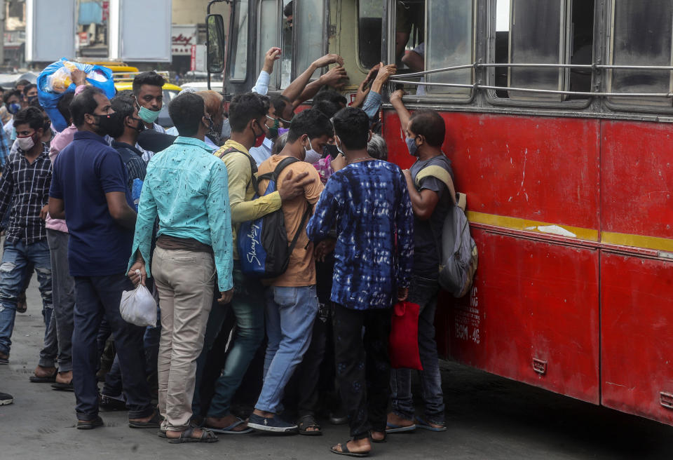 People wearing masks board a bus in Mumbai, India, Monday, April 5, 2021. India reported its biggest single-day spike in confirmed coronavirus cases since the pandemic began Monday, and officials in the hard-hit state home to Mumbai are returning to the closure of some businesses and places of worship in a bid to slow the spread. (AP Photo/Rafiq Maqbool)