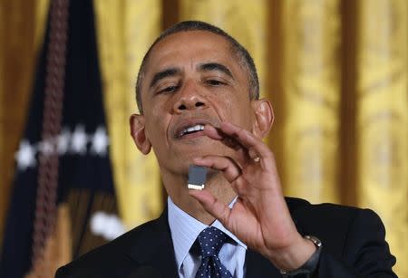 U.S. President Barack Obama holds up a SanDisk data storage card before awarding SanDisk founder Eli Harari with the National Medal of Technology and Innovation at a ceremony in the East Room of the White House in Washington November 20, 2014. REUTERS/Larry Downing