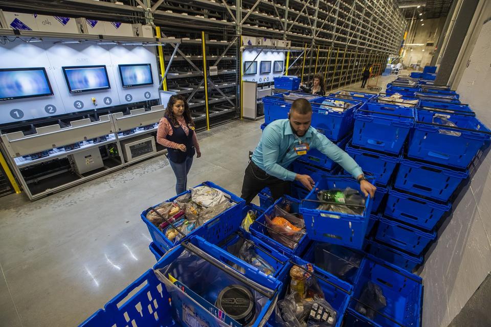 Walmart employees sort baskets full of food to meet customers' online grocery orders.