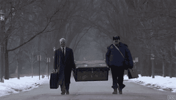 Two men carry a large trunk down the road in Planes Trains and Automobiles