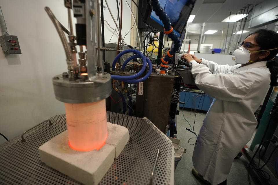 Research and development engineer Ravneet Kailey performs an experiment to produce iron without using carbon in a glowing lab cell, left, Wednesday, Jan. 25, 2023, at Boston Metal, in Woburn, Mass. The manufacture of ‘green steel’ moved one step closer to reality Friday, Jan. 27, as Boston Metal announced a $120 million investment from the world's second-largest steelmaker, ArcelorMittal. (AP Photo/Steven Senne)