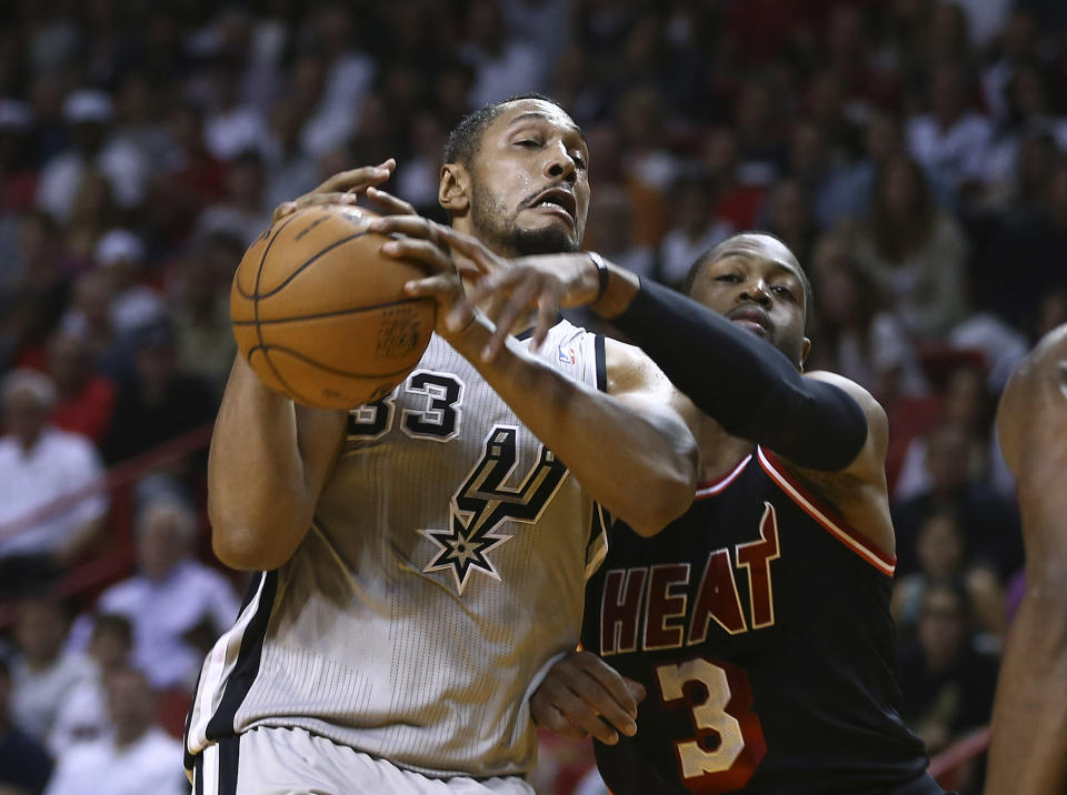 Miami Heat's Dwyane Wade (3) knocks the ball from San Antonio Spurs' Borks Diaw (33) hands during the first half of a NBA basketball game in Miami, Sunday, Jan. 26, 2014. (AP Photo/J Pat Carter)