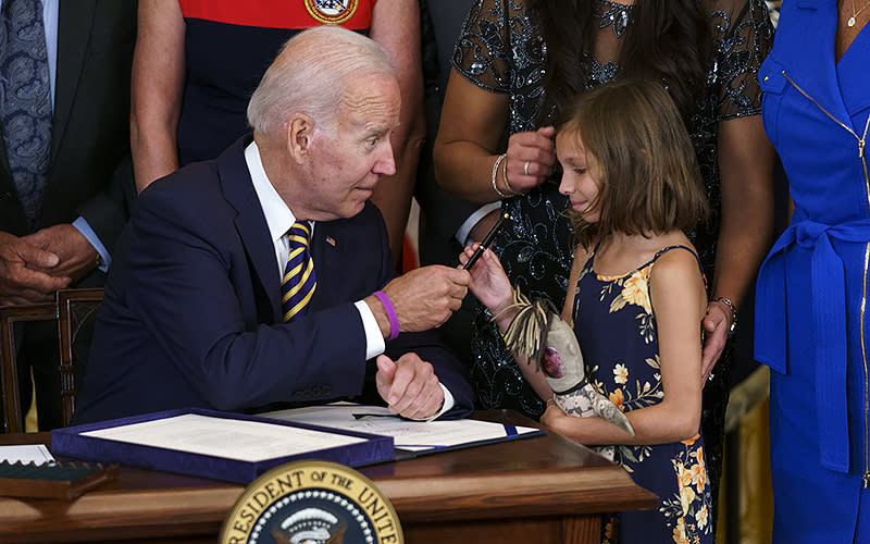 President Biden hands a pen to Brielle Robinson, daughter of the late Sgt. 1st Class Heath Robinson, during a ceremony to sign the Sgt. 1st Class Heath Robinson Honoring our Promises to Address Comprehensive Toxics Act on Aug. 10. <em>Greg Nash</em>