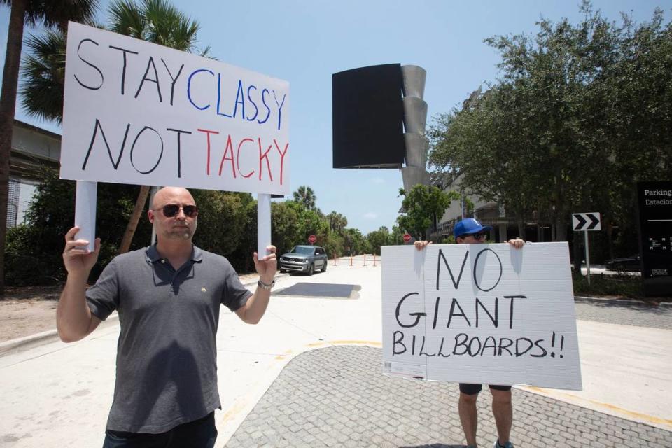 David Ward sostiene un cartel en protesta por la proliferación de gigantescas vallas publicitarias LED instaladas en espacios públicos de Miami, el domingo 19 de mayo de 2024. La protesta se organizó para conseguir apoyo para la revocación de un reciente cambio en la ley de Miami que permitió una gran valla publicitaria digital que ya se construyó en el Pérez Art Museum Miami.