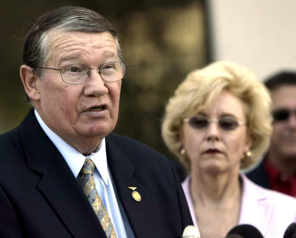 FILE - In this July 14, 2005, file photo, then-Rep. Randy "Duke" Cunningham, flanked by his wife Nancy, announces he will not seek re-election, during a news conference in San Marcos, Calif. When Rep. Cunningham admitted in 2005 to accepting $2.4 million in illegal gifts from defense contractors in exchange for government contracts and other favors, it was considered the largest bribery scandal in congressional history. The disgraced former San Diego congressman received one of the pardons issued Wednesday, Jan. 20, 2021, by President Donald Trump in the final hours of his term. (AP Photo/Lenny Ignelzi, Files)
