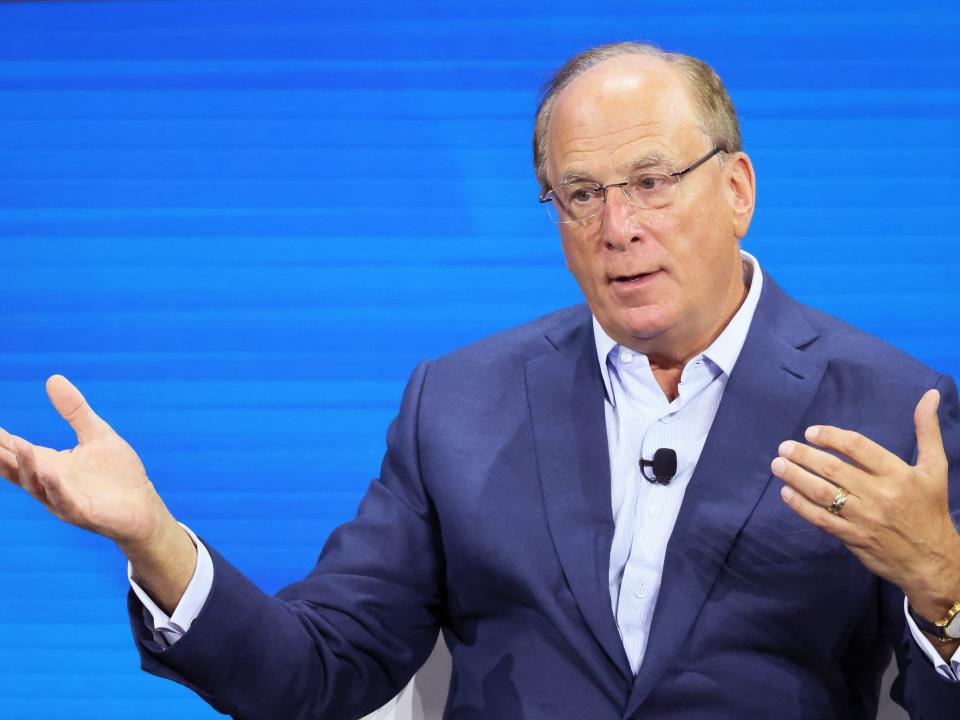 BlackRock CEO Larry Fink, pictured in November 2022, gesturing while sitting in front of a blue background.