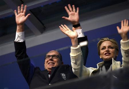 Prince Albert II of Monaco (L) and his wife Charlene wave from the presidential tribune at the opening ceremony of the 2014 Winter Olympics in Sochi, February 7, 2014. REUTERS/Lionel Bonaventure/Pool