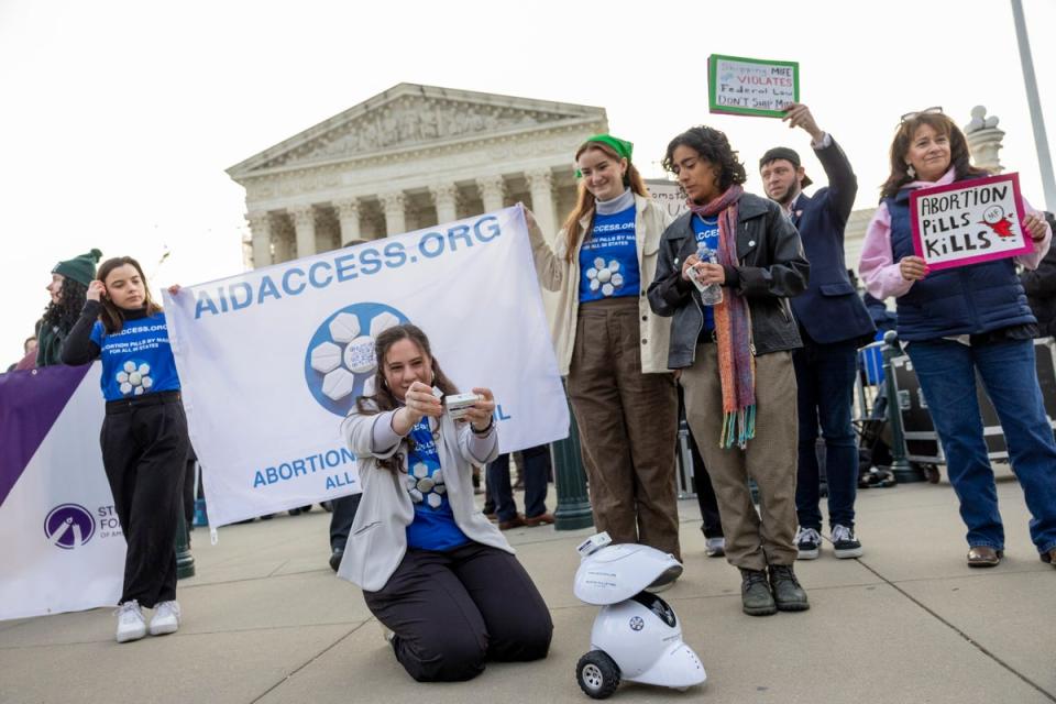 Mira Michels of Aid Access prepares to take the mifepristone pill in protest outside the US Supreme Court on 26 March. (AP)
