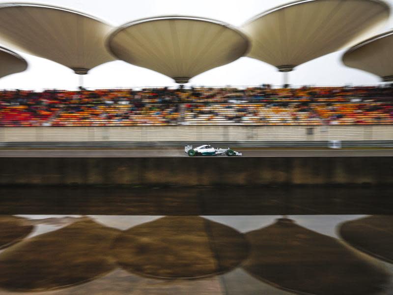 Nico Rosberg rast in Shanghai an den Tribünen vorbei, deren markante Dächer sich im Wasser eines Bassins spiegeln. Foto: Diego Azubel