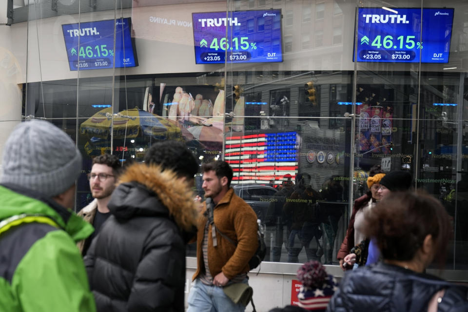 FILE - Pedestrians walk past the Nasdaq building as the stock price of Trump Media & Technology Group Corp. is displayed on screens, March 26, 2024, in New York. An auditing firm hired by Trump Media and Technology Group just 37 days ago was busted by the Securities and Exchange Commission for “massive fraud” — though not for any work it performed for former President Donald Trump’s media company. (AP Photo/Frank Franklin II, File)