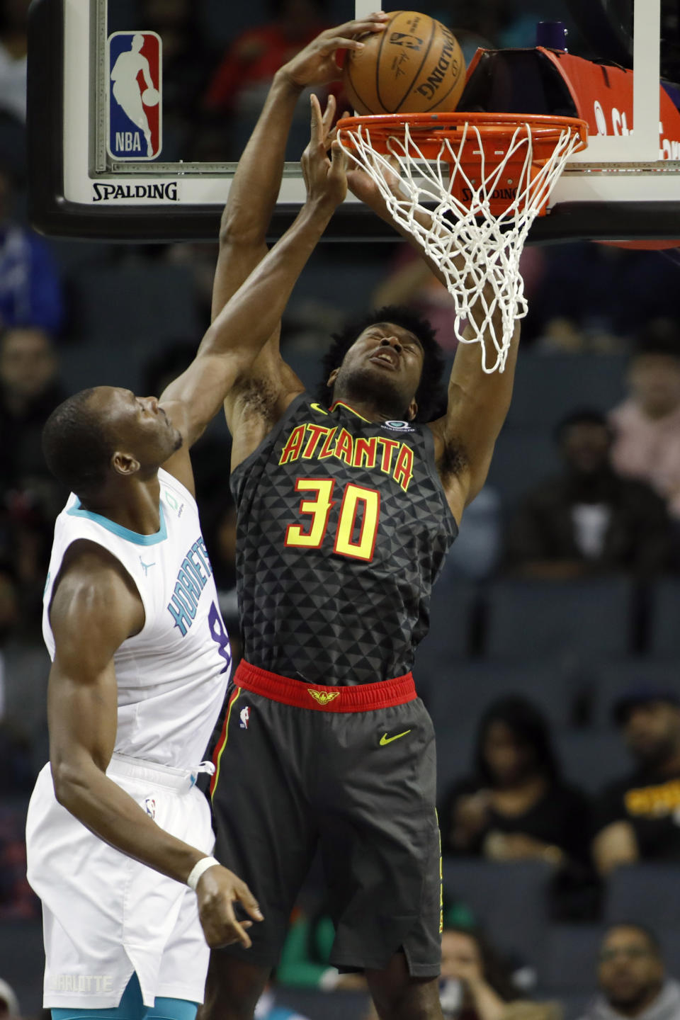 Atlanta Hawks' Damian Jones (30) dunks on Charlotte Hornets' Bismack Biyombo (8) during the first half of an NBA basketball game in Charlotte, N.C., Sunday, Dec. 8, 2019. (AP Photo/Bob Leverone)