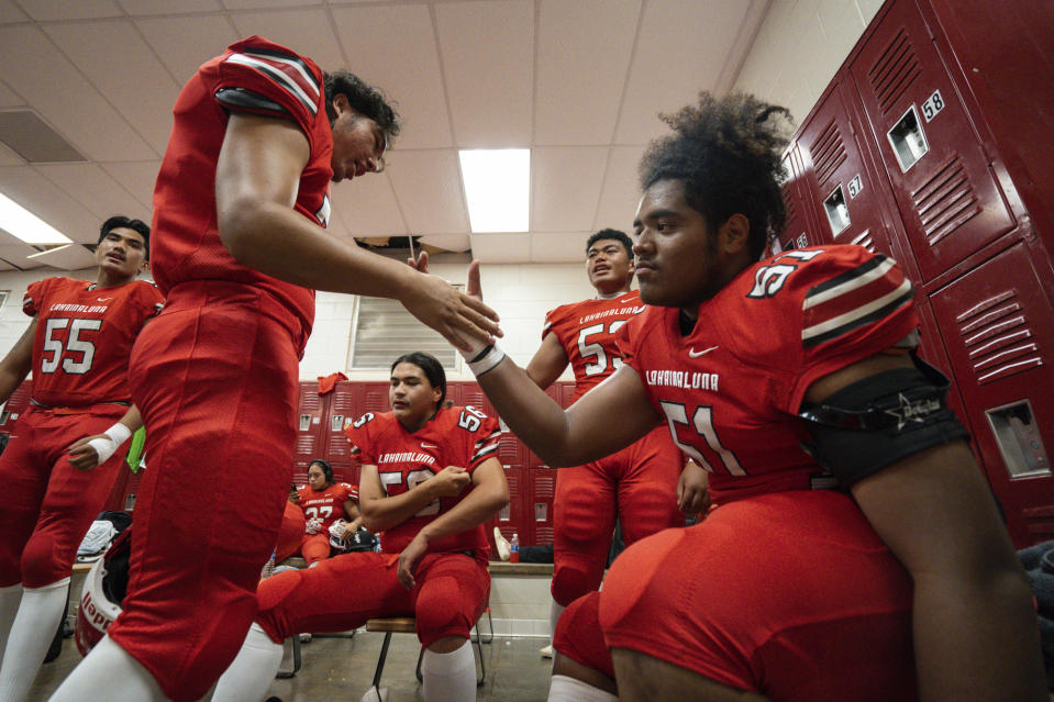Lahainaluna High School football team players get ready in the locker room at Sue D. Cooley Stadium, Saturday, Oct. 21, 2023, in Lahaina, Hawaii. Lahainaluna’s varsity and junior varsity football teams are getting back to normal since the devastating wildfire in August. (AP Photo/Mengshin Lin)