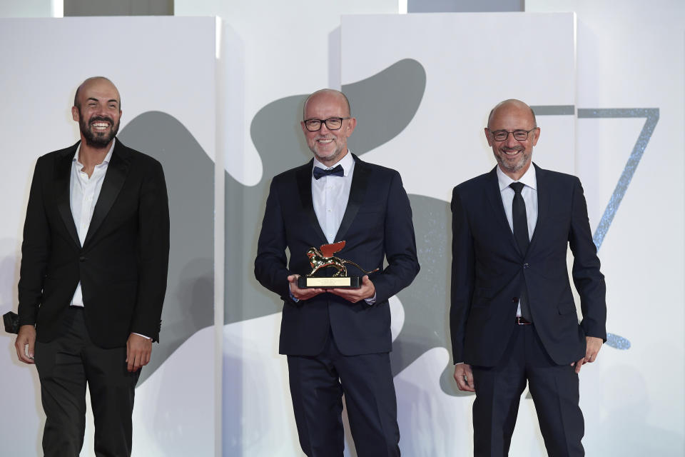 Disney's Marketing Director for Italy, Davide Romani, center, holds the Golden Lion Best Film award for "Nomadland", at the closing ceremony of 77th edition of the Venice Film Festival, in Venice, Italy, Saturday Sept. 12, 2020. Director Chloe Zhao’s “Nomadland,” a recession-era road trip drama starring Frances McDormand, has won the Golden Lion for best film at the Venice Film Festival, held against the backdrop of the coronavirus pandemic. (Gian Mattia D'Alberto/LaPresse via AP)