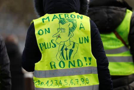 A protester wearing a yellow vest attends a demonstration with French unions against the French government policies in front of the sport hall "La Maison du Handball" during a visit of French President Emmanuel Macron in Creteil near Paris, France, January 9, 2019. The slogan reads "Macron we're broke". REUTERS/Charles Platiau