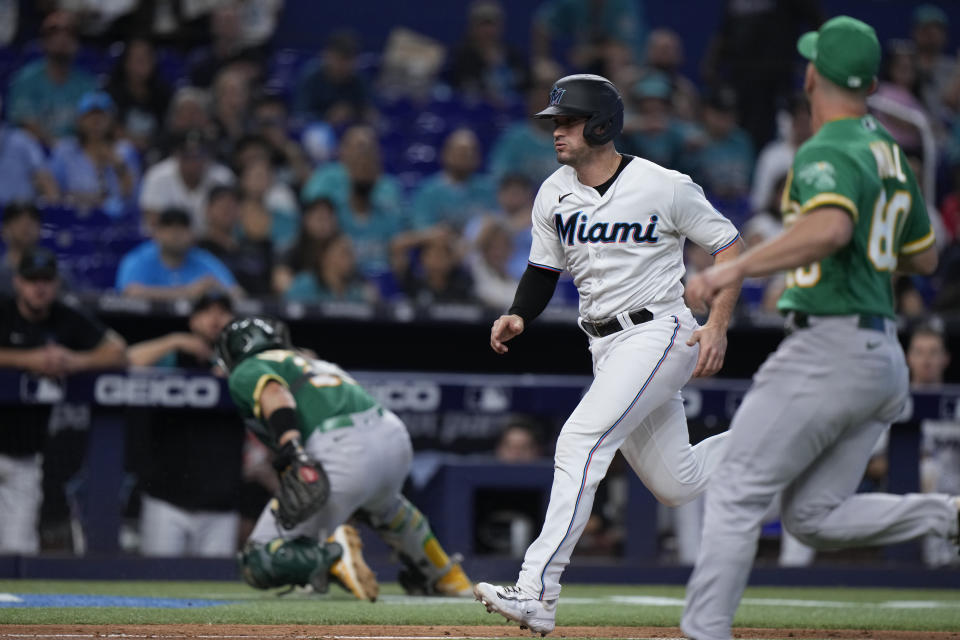 Miami Marlins' Nick Fortes, center, heads to home to score on a passed ball by Oakland Athletics catcher Shea Langeliers, left rear, as pitcher Sam Moll runs to help during the eighth inning of a baseball game, Sunday, June 4, 2023, in Miami. (AP Photo/Wilfredo Lee)