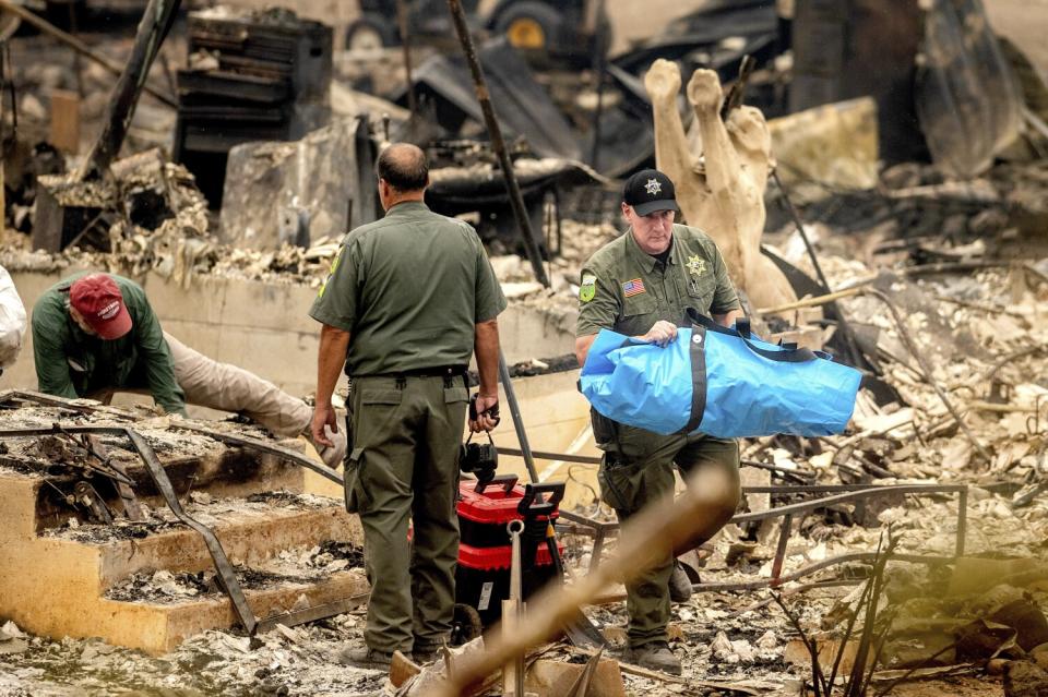 A sheriff's deputy carries the remains of a fire victim Monday.