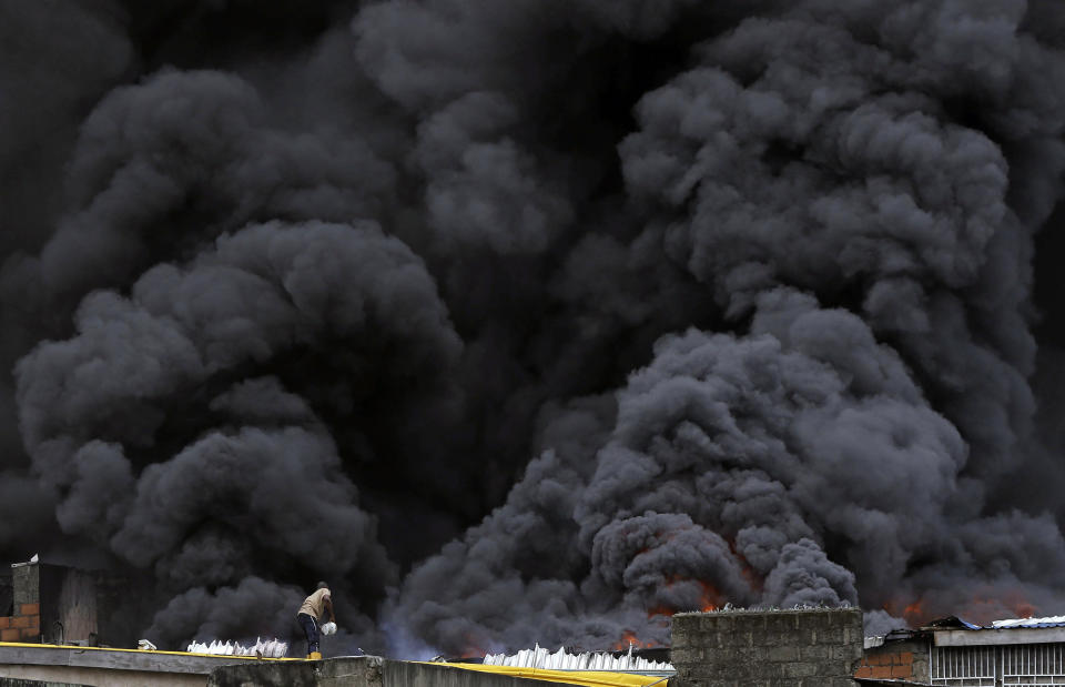 A man with a bucket tackles a blaze as smoke rises from a fire in downtown Lagos, Nigeria, Tuesday, Nov. 5, 2019. (Photo: Sunday Alamba/AP)