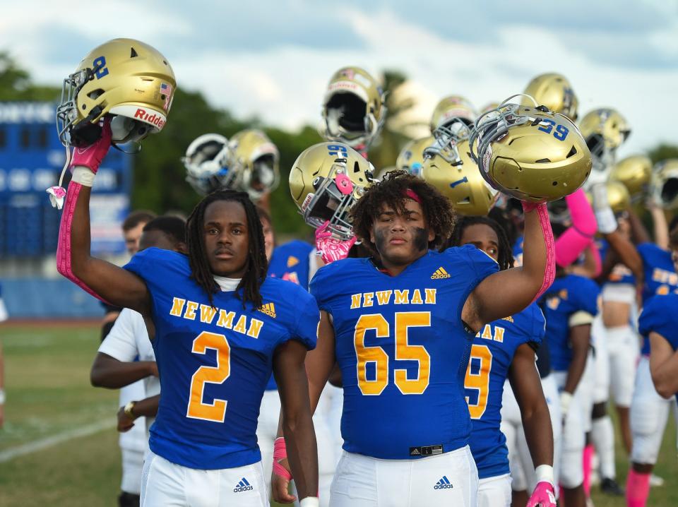 Cardinal Newman players Josh Philostin (2) and Taesean Trent (65) salute after the national anthem before a 40-7 victory over John Carroll Monday night in West Palm Beach.