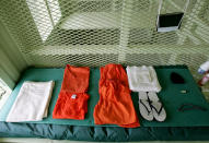 GUANTANAMO BAY, CUBA - AUGUST 23: A uniform and other supplies that are given to detainees lie on a bed in a cell at Camp Delta at Guantanamo Naval Base August 23, 2004 in Guantanamo, Cuba. On August 24, preliminary hearings will begin for four suspected Al Qaeda associates charged by the U.S. with war crimes as they appear before a commission of five military officers. (Photo by Mark Wilson/Getty Images)