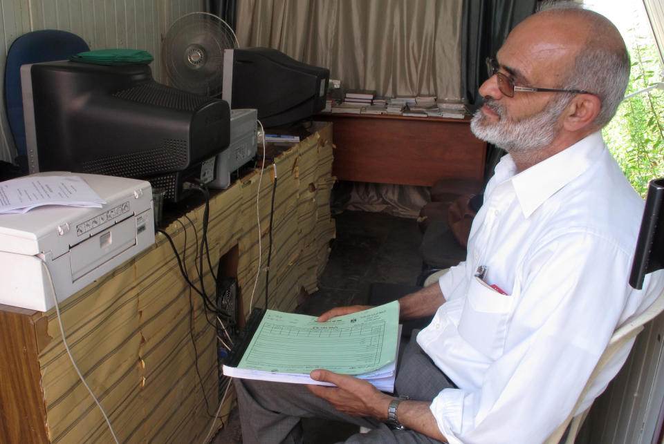 In this photo taken Wednesday, Aug. 29, 2012, a Palestinian marriage celebrant holds a notebook of ready-to-fill-in marriage certificates in his trailer-style office in the West Bank city of Ramallah, outside the Islamic court where Muslim Palestinians register marriages and file for divorce. (AP Photo/Diaa Hadid)