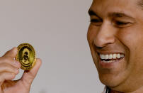 Indian cricketer Sachin Tendulkar displays a limited edition 10 gram gold coin with an embossed image of himself after unveiling it on Akshaya Tritiya in Mumbai on May 13, 2013. A total of 100, 000 limited edition 10 gram Tendulkar Gold coins priced at INR 34,000 (USD 618) will be available for both online purchase and at retail stores of leading jewellers across the country. Akshaya Tritiya is considered to be an auspicious day in the Hindu calendar to buy valuables and people generally flock to buy gold on this day in the belief that it will increase their wealth. AFP PHOTO/ Indranil MUKHERJEE