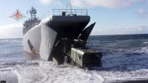 In this handout photo released by Russian Defense Ministry Press Service, A Bastion missile launcher moves ashore from an amphibious landing vehicles on the Matua Island, part of the Kurils Islands chain, in Russia, Thursday, Dec. 2, 2021. The Russian military has deployed the Bastion coastal defense missile systems on the Matua Island, which is close to several islands also claimed by Japan, a move intended to underline Moscow's firm stance in the dispute. (Russian Defense Ministry Press Service via AP)