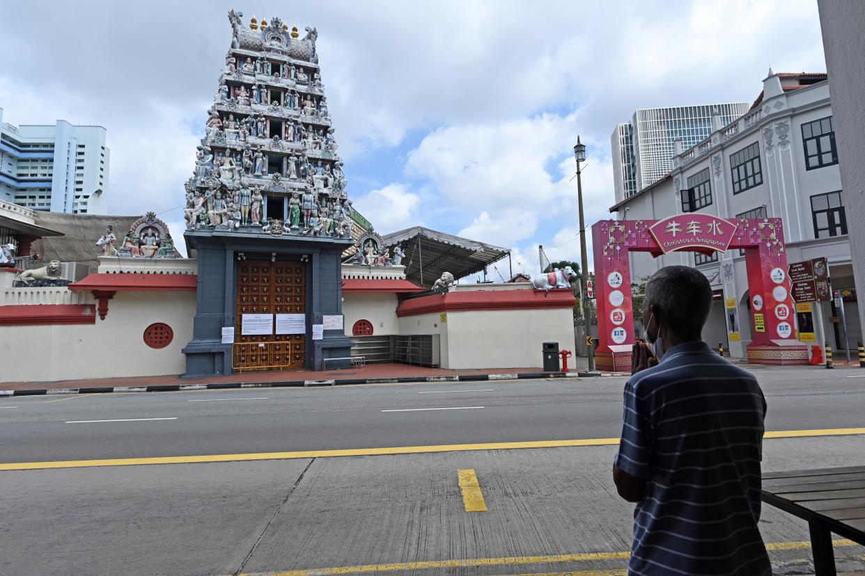 A man wearing a facemask as a preventive measure against the spread of the COVID-19 coronavirus prays opposite a Hindu temple in the Chinatown district of Singapore on April 13, 2020. (Photo by ROSLAN RAHMAN / AFP) (Photo by ROSLAN RAHMAN/AFP via Getty Images)