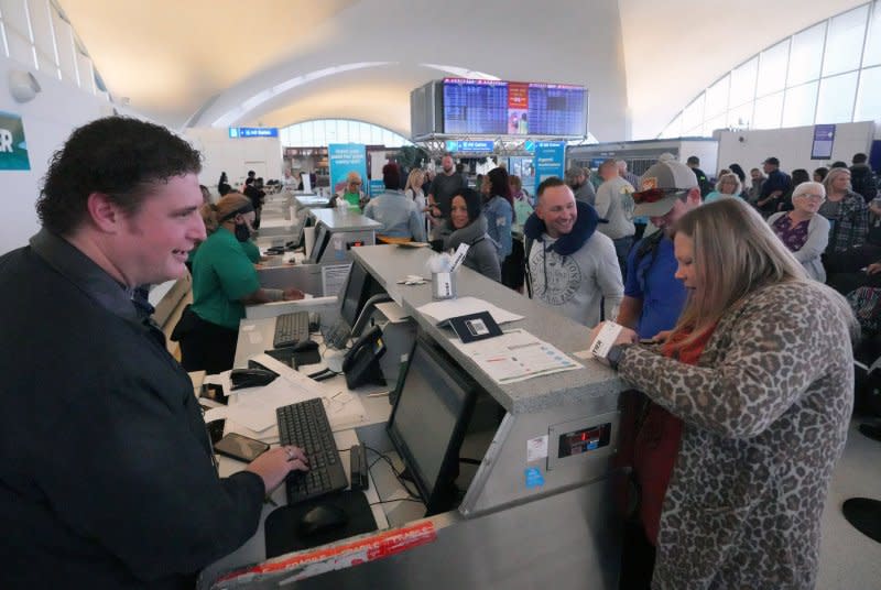 A Frontier Airlines ticket agent waits on those in line for the inaugural Feb. 2023 flight to Montego Bay, from St. Louis-Lambert Airport in Missouri. The Denver-headquartered Frontier Airlines in March said they would guarantee an empty middle seat on some of its flights in a new upgrade deal. File Photo by Bill Greenblatt/UPI