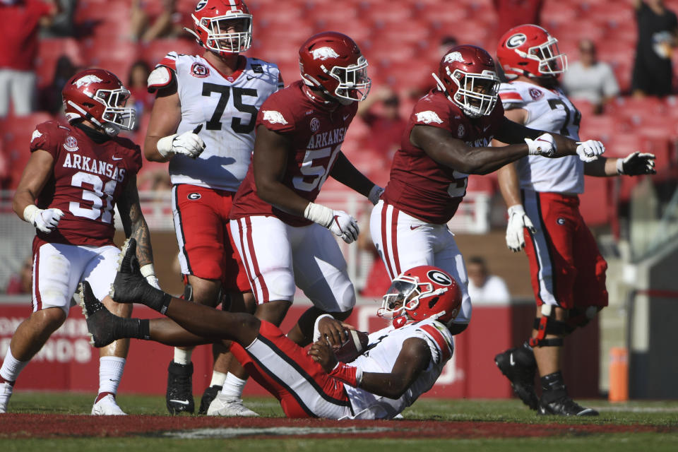 Arkansas defenders Grant Morgan (31), Eric Gregory, (50) and Dorian Gerald (5) celebrate after bringing down Georgia quarterback D'Wan Mathis (2) for a loss during the first half of an NCAA college football game in Fayetteville, Ark., Saturday, Sept. 26, 2020. (AP Photo/Michael Woods)