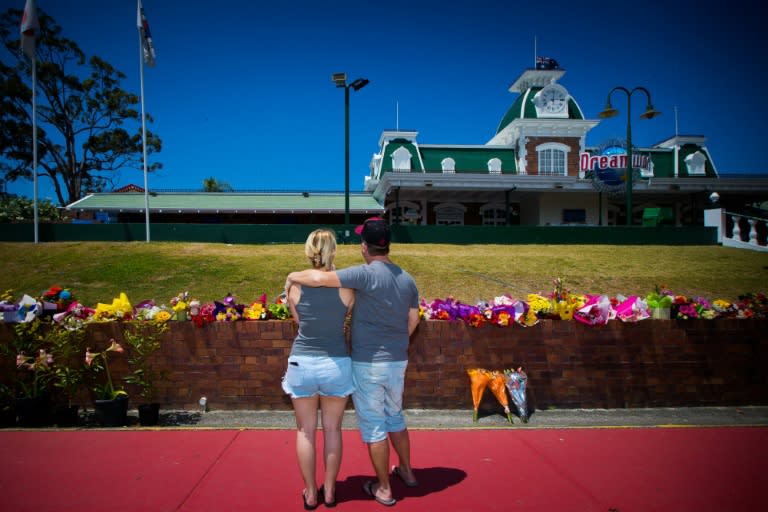 Wayne Marmo hugs his daughter Emily as they lay flowers at a makeshift floral tribute outside the Dreamworld theme park on the Gold Coast on October 26, 2016