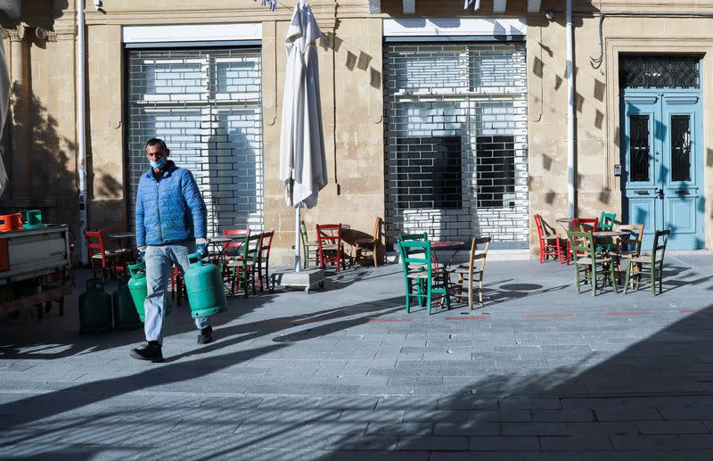 A man wearing a protective face mask carries gas bottles amid the coronavirus disease (COVID-19) outbreak in Nicosia