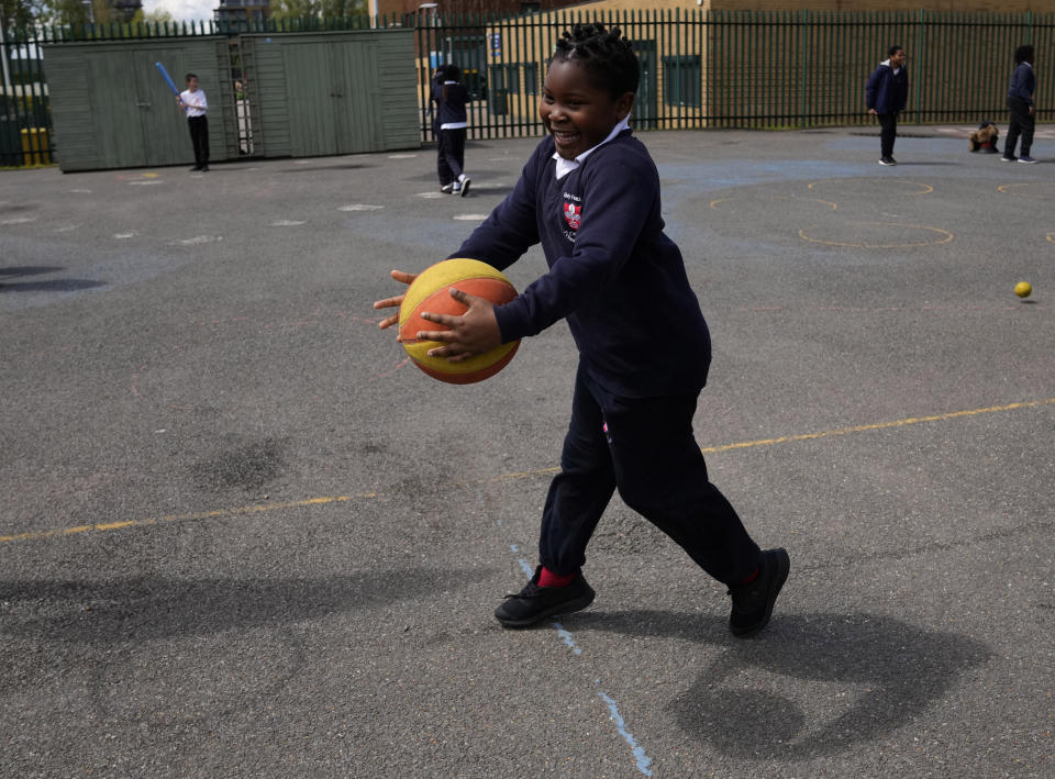 Joel catches a basketball as he plays in the playground of the Holy Family Catholic Primary School in Greenwich, London, Wednesday, May 19, 2021. (AP Photo/Alastair Grant)