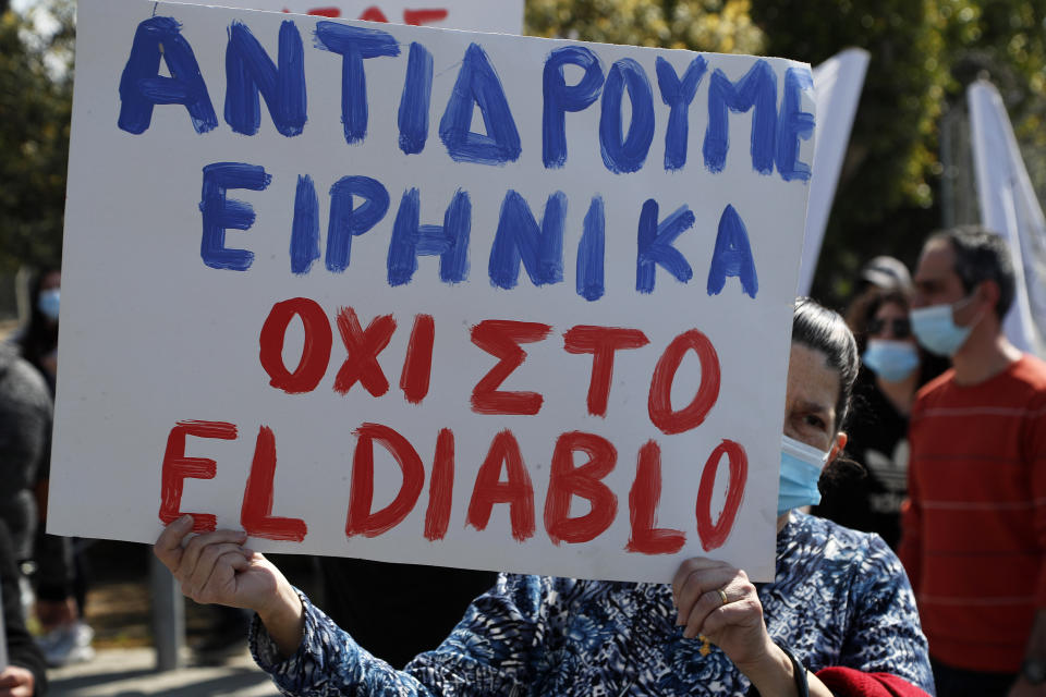 A protestor holds a banner reading in Greek "We react in Peace, not to the El Diablo" , outside Cyprus' national broadcasting building, during a protest, in capital Nicosia, Cyprus, Saturday, March 6, 2021. The Orthodox Church of Cyprus is calling for the withdrawal of the country’s controversial entry into this year’s Eurovision song context titled “El Diablo”, charging that the song makes an international mockery of country’s moral foundations by advocating “our surrender to the devil and promoting his worship.” (AP Photo/Petros Karadjias)