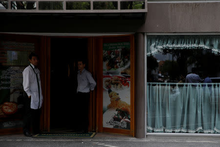 Workers stand at the door of a restaurant during a blackout in Caracas, Venezuela March 7, 2019. REUTERS/Carlos Garcia Rawlins