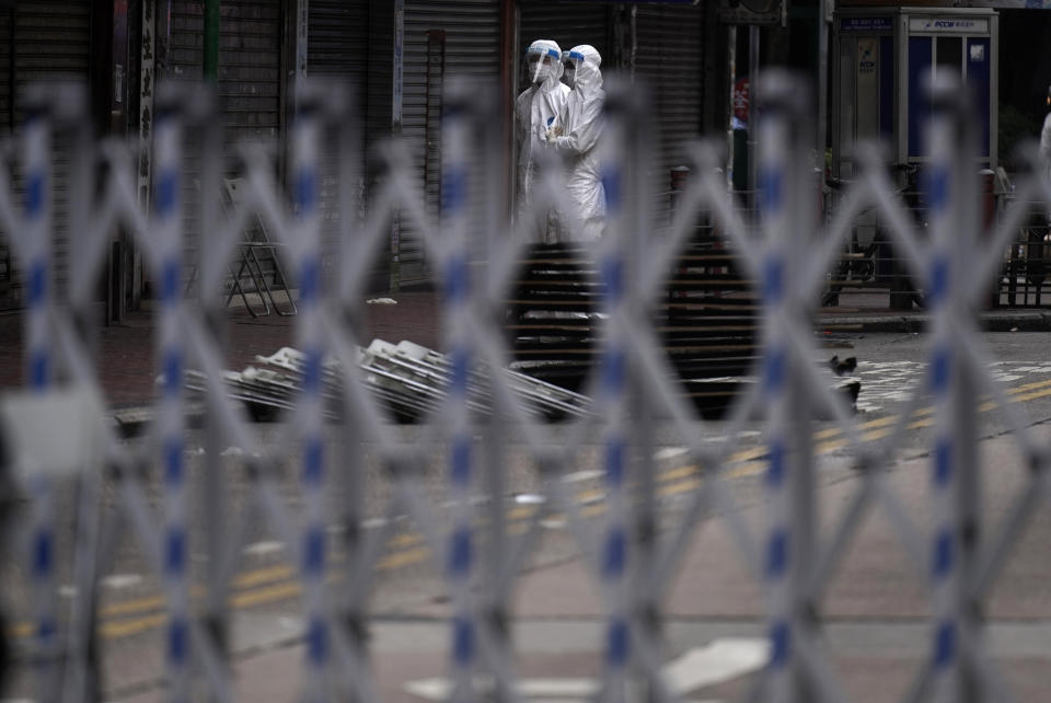 Government workers wearing personal protective equipment stand guard at the closed area in Jordan district, in Hong Kong, Sunday, Jan. 24, 2021. Thousands of Hong Kong residents were locked down Saturday in an unprecedented move to contain a worsening outbreak in the city, authorities said. (AP Photo/Vincent Yu)