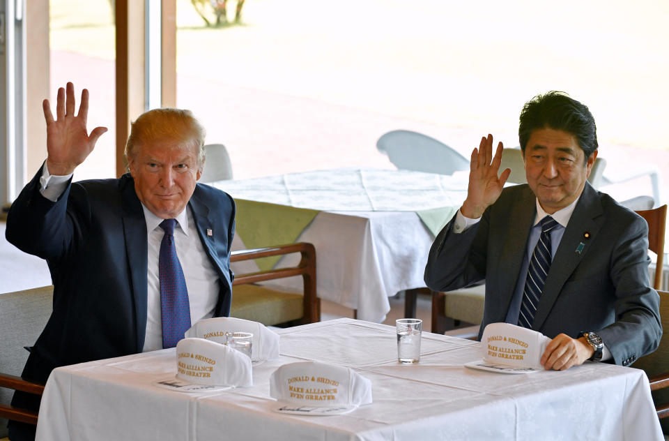 President Donald Trump and Japanese Prime Minister Shinzo Abe wave to reporters after they signed hats reading 'Donald and Shinzo, Make Alliance Even Greater'.