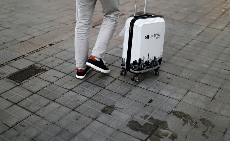 FILE PHOTO: A tourist walks with his suitcase, amid the coronavirus disease outbreak, in Barcelona