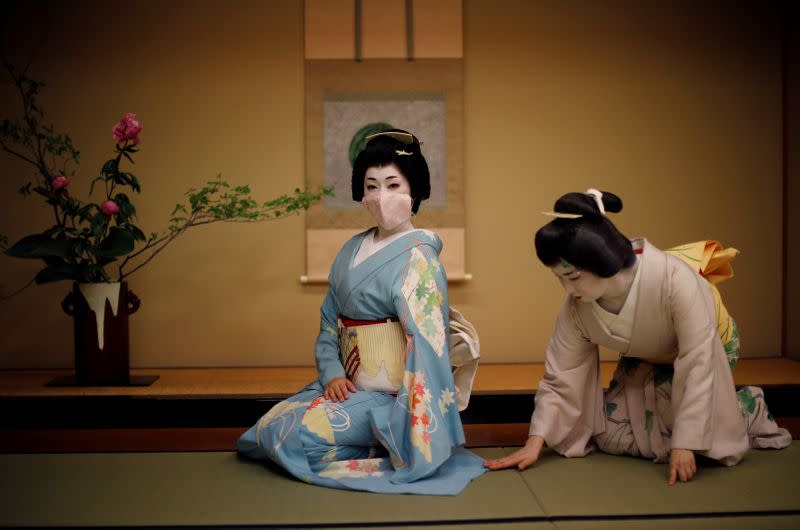 Mayu ajusta el kimono de Koiku, quienes son geishas, ya que Koiku usa una máscara protectora para posar para una fotografía, antes de trabajar en una fiesta organizada por clientes, donde se entretendrán con otras geishas, en Asada, un lujoso restaurante japonés, durante el brote de coronavirus (COVID-19), en Tokio, Japón