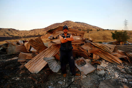 Peruvian immigrant, Segundo Altamirano, poses in front of the debris of his home at a shack camp after an accidental fire in Santiago, Chile, December 14, 2016. Picture taken December 14, 2016. REUTERS/Ivan Alvarado