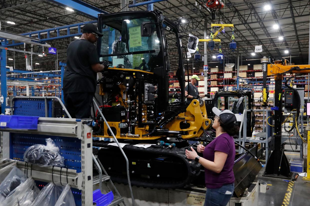 Caterpillar employees install the passenger cab on a mini-hydraulic excavator on the assembly line on Wednesday, when the company celebrated its 10-year anniversary.