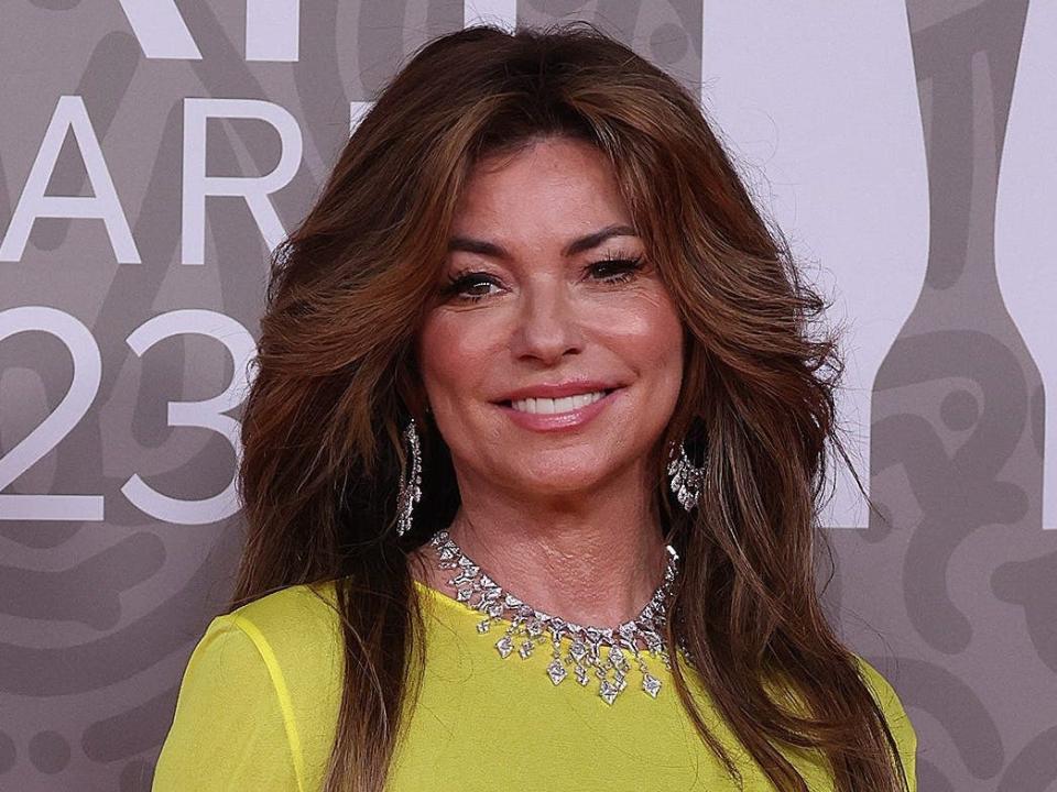 Shania Twain attends the 2023 Brit Awards in a long-sleeve yellow gown.