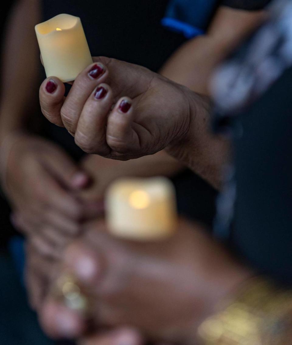 Two women hold battery powered candles during a vigil hosted by the Farmworker Association of Florida.