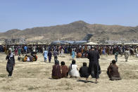 FILE - Hundreds of people gather near a U.S. Air Force C-17 transport plane at the perimeter of the international airport in Kabul, Afghanistan, on Aug. 16, 2021. A year after America's tumultuous and deadly withdrawal from Afghanistan, assessments of its impact are divided — and largely along partisan lines.(AP Photo/Shekib Rahmani, File)