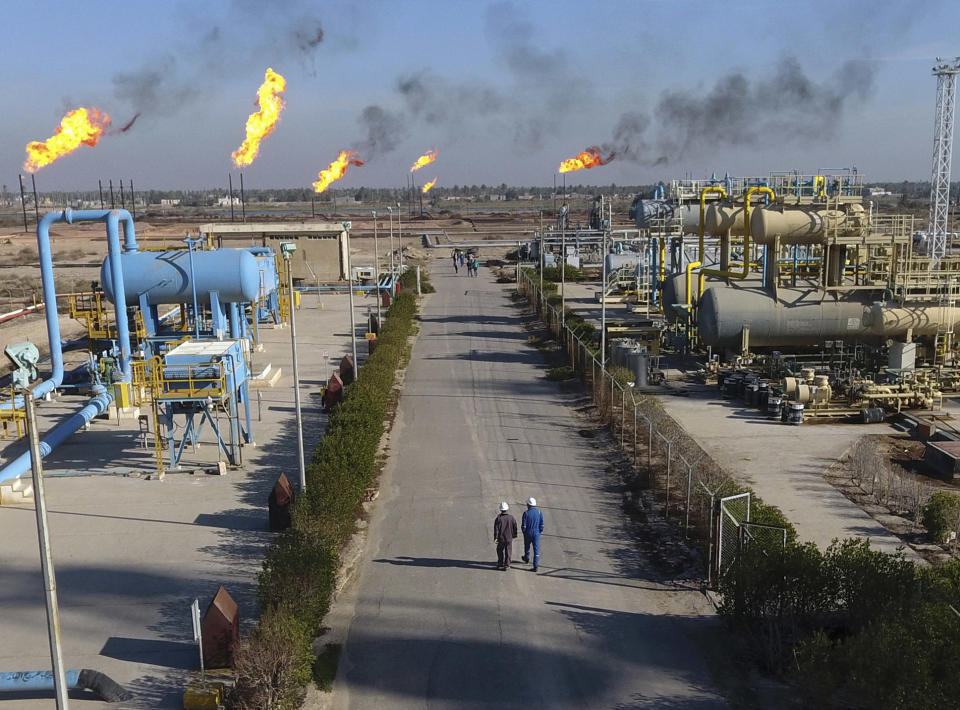 FILE - In this Jan. 12, 2017 file photo, laborers walk down a path in the Nihran Bin Omar field north of Basra, Iraq, 340 miles (550 kilometers) southeast of Baghdad. The historic crash in oil prices in the wake of the novel coronavirus pandemic is reverberating across the Middle East as crude-dependent countries scramble to offset losses from a key source of state revenue. The economies of all the Arab Gulf oil exporters are expected to contract this year. Iraq faces the most dire situation, and officials are trying to find ways to cut spending. (AP Photo/Nabil al-Jurani, File)