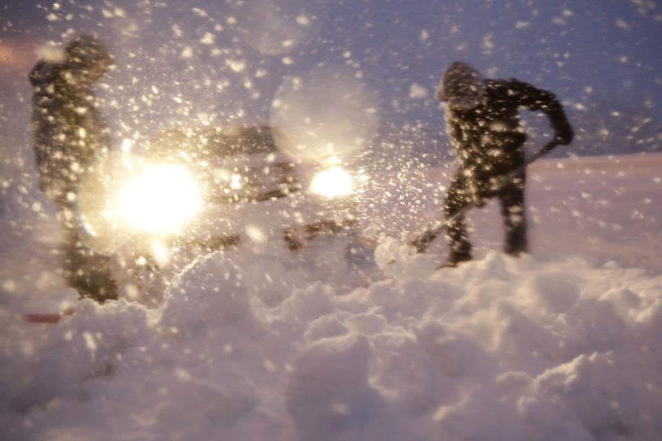 <p>Men shovel snow in attempt to free a vehicle stuck on a snowbank along Route 23 during a snowstorm, March 7, 2018, in Wayne, N.J. (Photo: Julio Cortez/AP) </p>