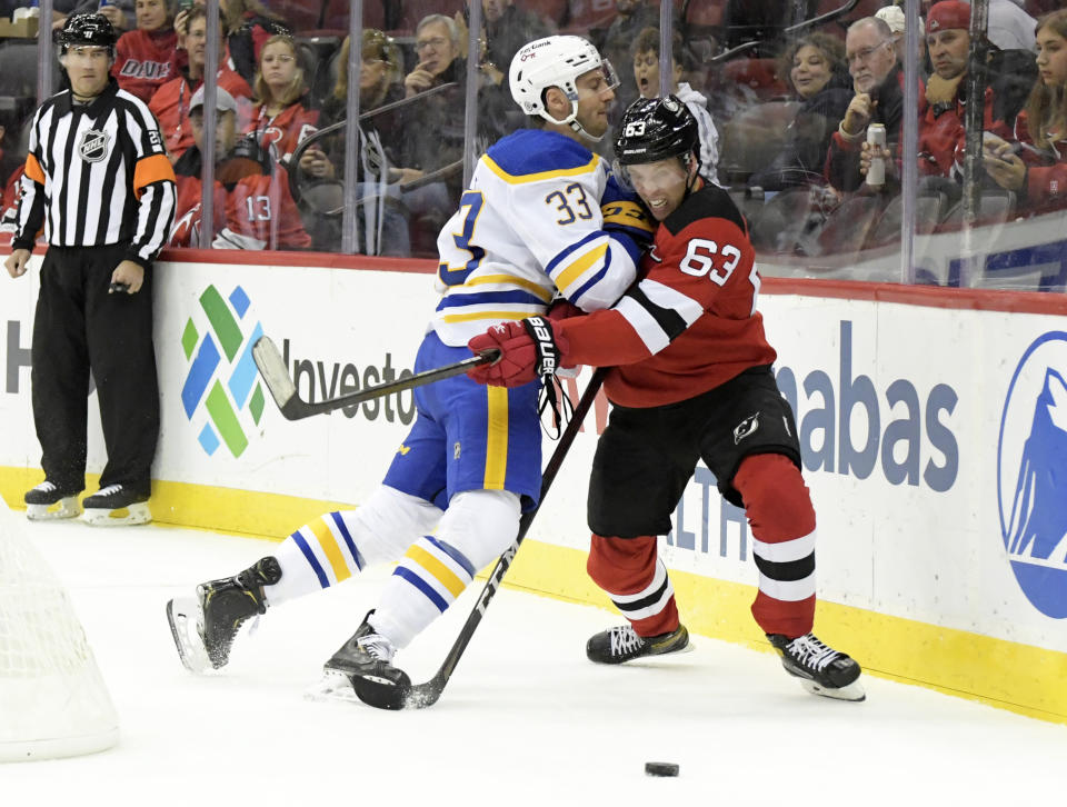 Buffalo Sabres defenseman Colin Miller (33) checks New Jersey Devils left wing Jesper Bratt (63) during the first period of an NHL hockey game Saturday, Oct. 23, 2021, in Newark, N.J. (AP Photo/Bill Kostroun)