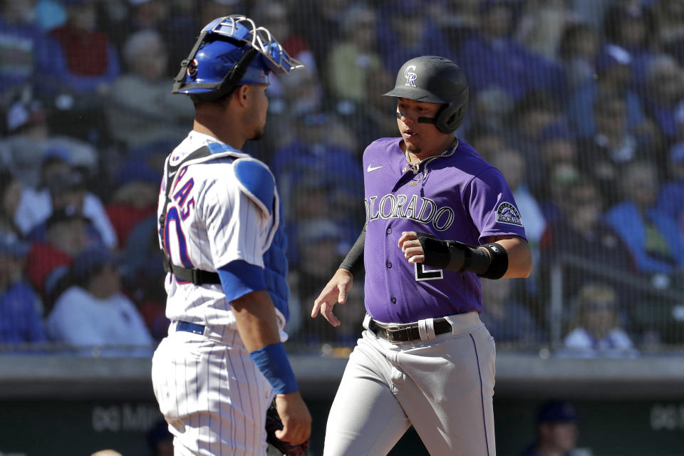 Colorado Rockies' Yonathan Daza scores on a double hit by teammate Drew Butera during the second inning of a spring training baseball game as Chicago Cubs catcher Willson Contreras looks on, Tuesday, Feb. 25, 2020, in Mesa, Ariz. (AP Photo/Matt York)