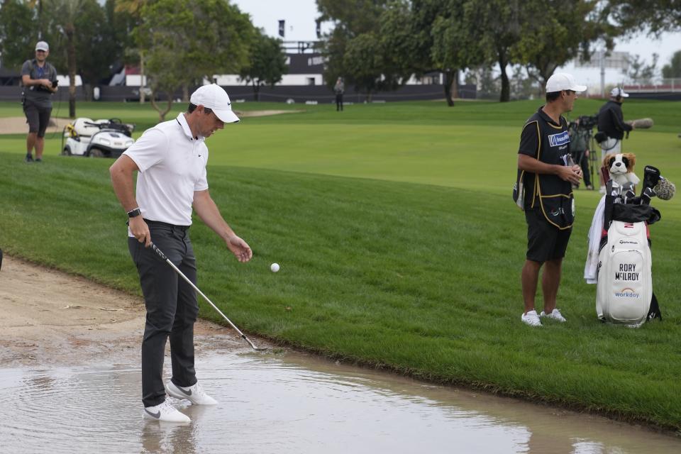 Rory McIlroy of Northern Ireland retrieves his ball from water on the 10th hole during the first round of the Dubai Desert Classic, in Dubai, United Arab Emirates, Thursday, Jan. 26, 2023. (AP Photo/Kamran Jebreili)